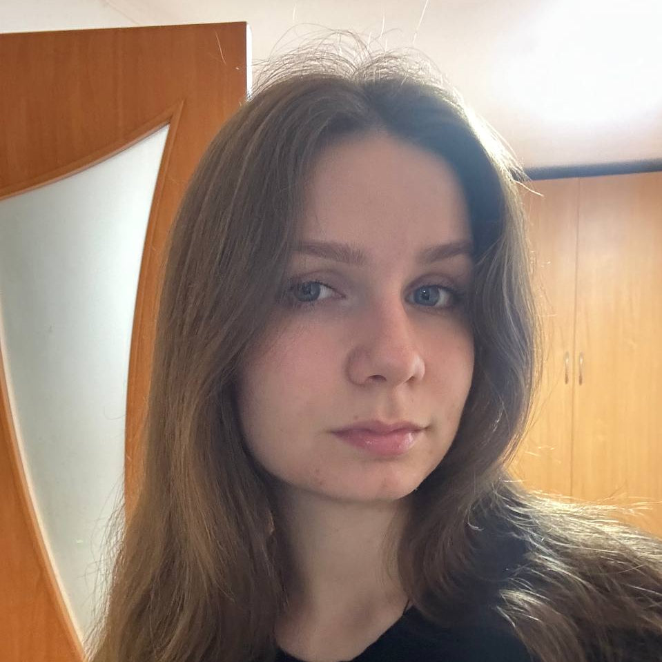 Clara Moon with long brown hair wearing a black top in an indoor setting.